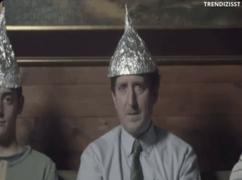 A Man Wearing A Tin Foil Hat Is Sitting Next To Two Other People GIF