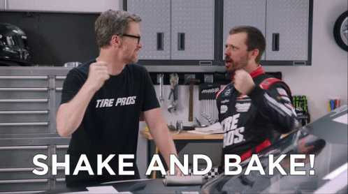 A Man Wearing A Tire Pros Shirt Stands Next To Another Man In A Garage GIF