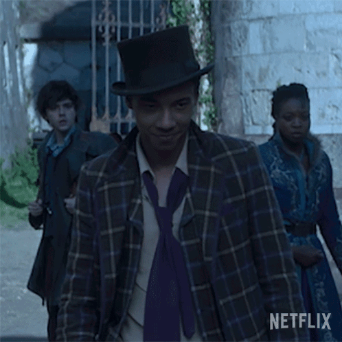 A Man Wearing A Top Hat And A Purple Tie Is Walking Down The Street . GIF