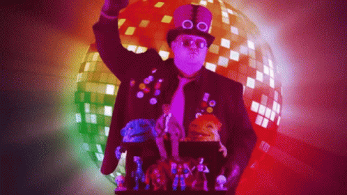 A Man Wearing A Top Hat And Glasses Is Standing In Front Of A Disco Ball GIF
