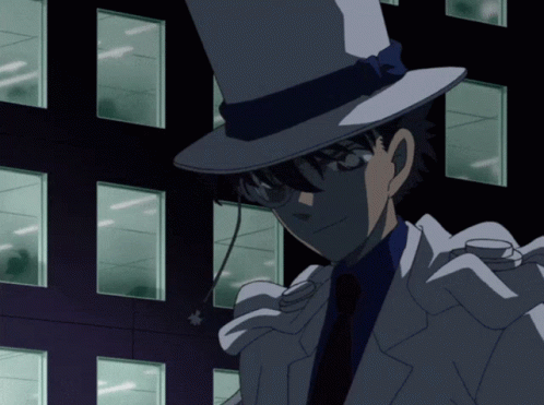 A Man Wearing A Top Hat And Glasses Stands In Front Of A Dark Building GIF