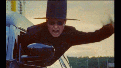 A Man Wearing A Top Hat And Sunglasses Is Flying Out Of A Car Window GIF