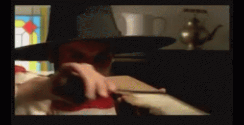 A Man Wearing A Top Hat Is Holding A Red Object GIF