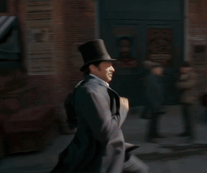A Man Wearing A Top Hat Is Running Down A Street GIF