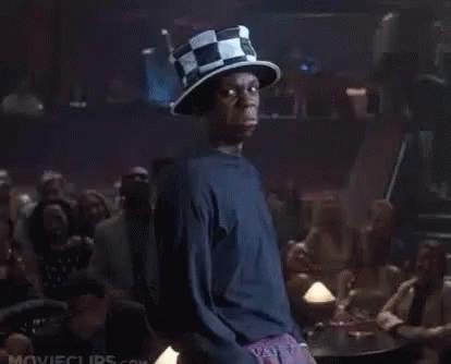A Man Wearing A Top Hat Is Standing In Front Of A Crowd Of People In A Bar . GIF