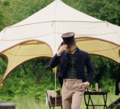 A Man Wearing A Top Hat Is Standing In Front Of A Tent GIF