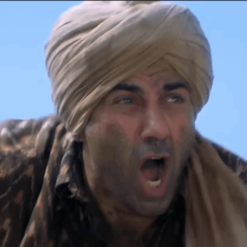 A Man Wearing A Turban And A Scarf Is Making A Funny Face GIF