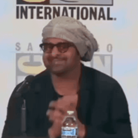 A Man Wearing A Turban And Glasses Is Holding A Bottle Of Water . GIF