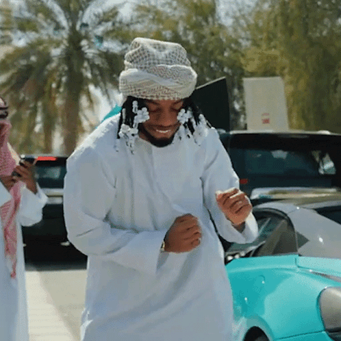 A Man Wearing A Turban Is Standing In Front Of A Car GIF