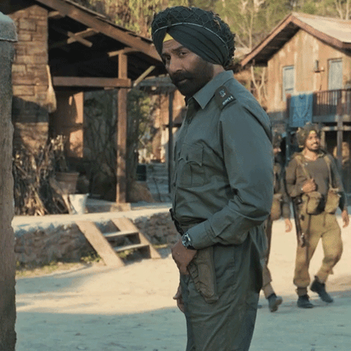 A Man Wearing A Turban Stands In Front Of A Building GIF