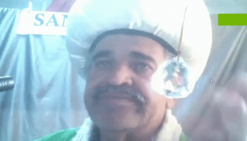 A Man Wearing A Turban Stands In Front Of A Sign That Says Sai On It GIF