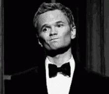 A Man Wearing A Tuxedo And Bow Tie Is Making A Funny Face . GIF