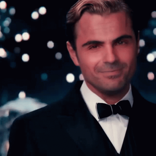 A Man Wearing A Tuxedo And Bow Tie Smiles For The Camera GIF