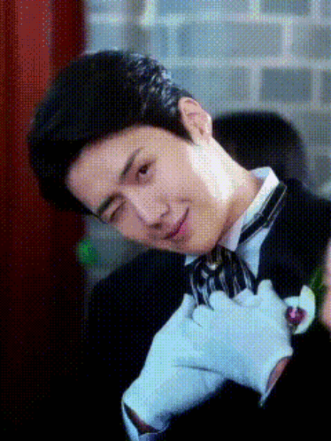 A Man Wearing A Tuxedo And White Gloves Is Making A Face GIF