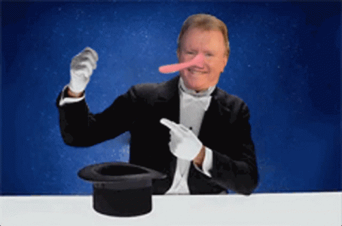 A Man Wearing A Tuxedo And White Gloves Is Pointing At A Top Hat GIF