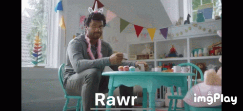 A Man Wearing A Unicorn Headband Sits At A Table With Cupcakes And Says Rawr GIF