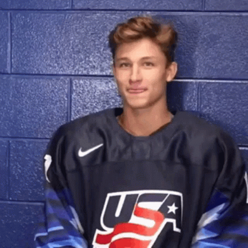 A Man Wearing A Usa Jersey Is Standing In Front Of A Blue Wall . GIF
