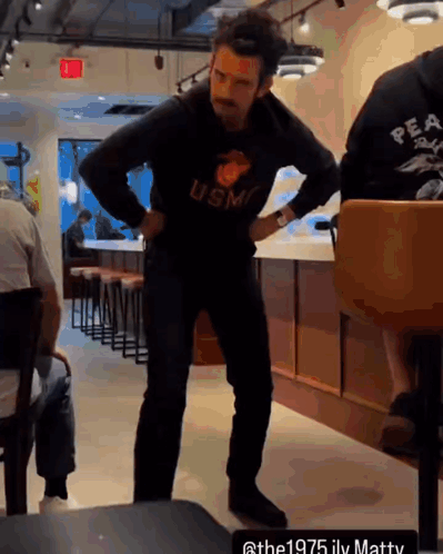 A Man Wearing A Usmc Sweatshirt Stands In A Restaurant GIF