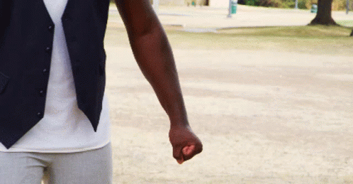 A Man Wearing A Vest And A White Shirt Is Holding A Purple Object In His Fist . GIF
