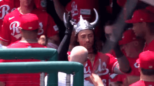 A Man Wearing A Viking Hat Stands In A Crowd Of Baseball Players Wearing Red Jerseys With The Letter R On Them GIF
