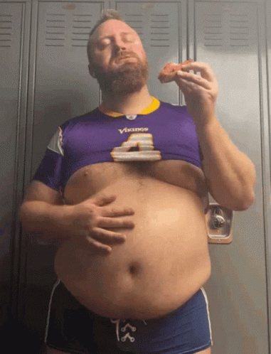 A Man Wearing A Vikings Jersey Is Eating A Slice Of Pizza GIF
