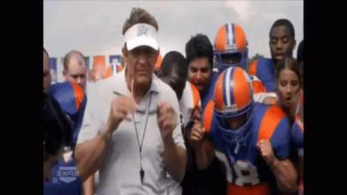 A Man Wearing A Visor With A Star On It Is Surrounded By Football Players GIF