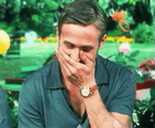 a man wearing a watch is covering his mouth with his hands .