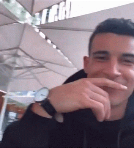 A Man Wearing A Watch Is Laughing And Covering His Mouth GIF