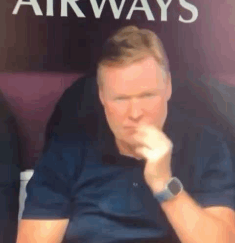 A Man Wearing A Watch Is Sitting In Front Of A Sign That Says `` Airways '' . GIF