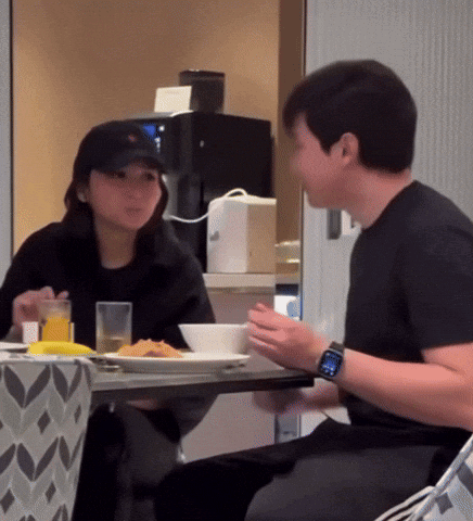 A Man Wearing A Watch Sits At A Table With A Woman Eating Food GIF