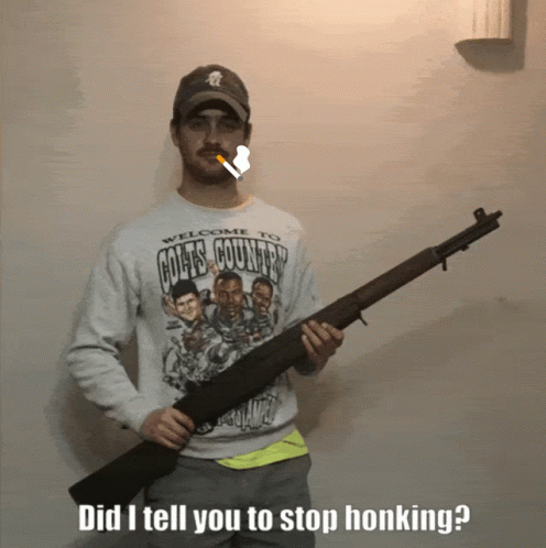 A Man Wearing A Welcome To Goats Country Sweatshirt Holds A Shotgun GIF