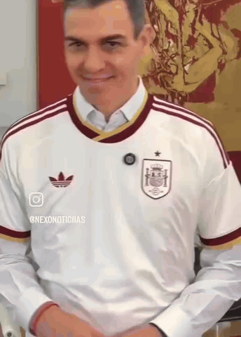 a man wearing a white adidas shirt is smiling and looking down