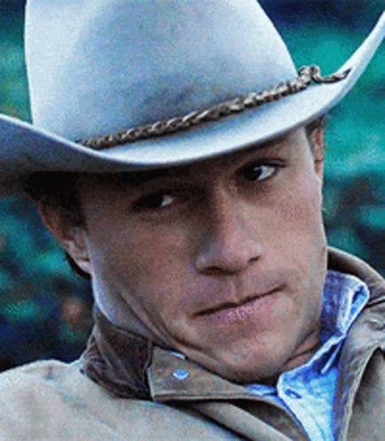 A Man Wearing A White Cowboy Hat And A Brown Jacket GIF