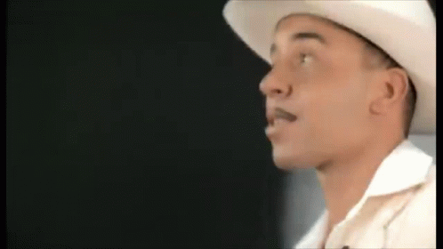 A Man Wearing A White Cowboy Hat And A White Shirt Is Looking To The Side . GIF