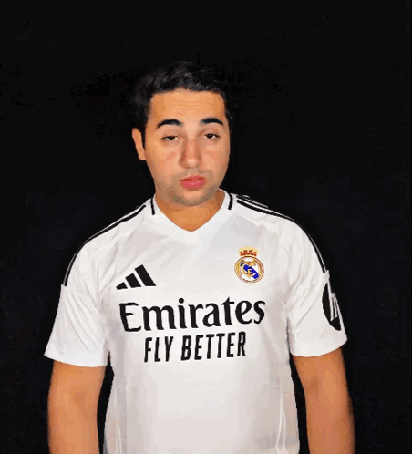 a man wearing a white emirates fly better jersey blows a kiss