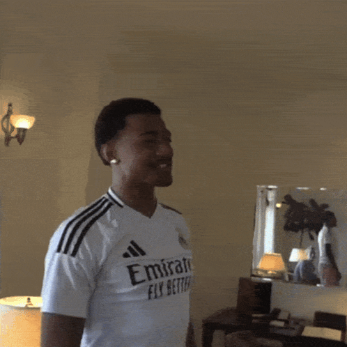 A Man Wearing A White Emirates Fly Better Shirt Is Making A Heart Shape With His Hands GIF