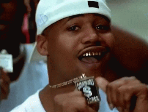 A Man Wearing A White Hat And A Necklace Is Holding A Coin In His Hand . GIF