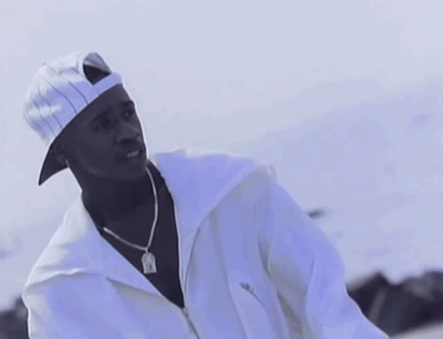 A Man Wearing A White Hat And A White Jacket Has A Pendant Around His Neck That Says Jesus GIF