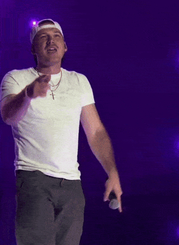 A Man Wearing A White Hat And A White T-Shirt Holds A Microphone GIF