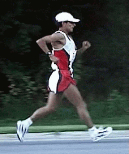 A Man Wearing A White Hat And Sunglasses Is Running On A Road GIF