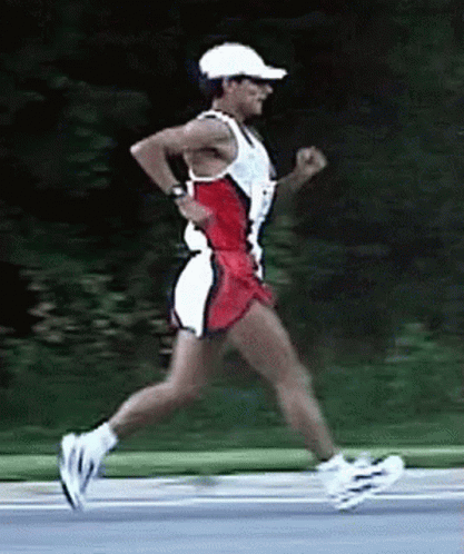 A Man Wearing A White Hat And Sunglasses Is Running On A Road GIF