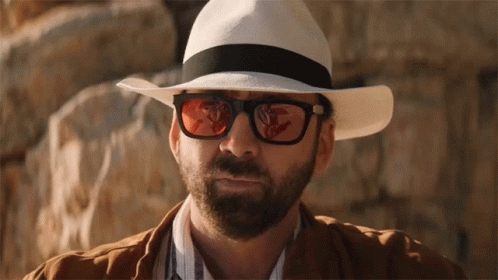 A Man Wearing A White Hat And Sunglasses Looks At The Camera GIF