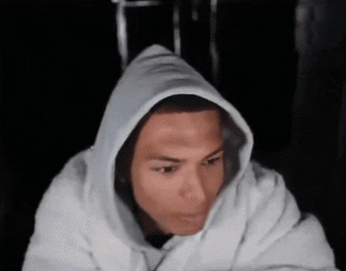 a man wearing a white hoodie looks at the camera