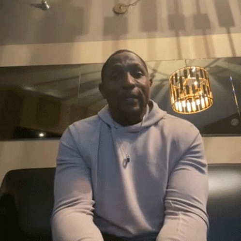 A Man Wearing A White Hoodie Sits On A Couch GIF