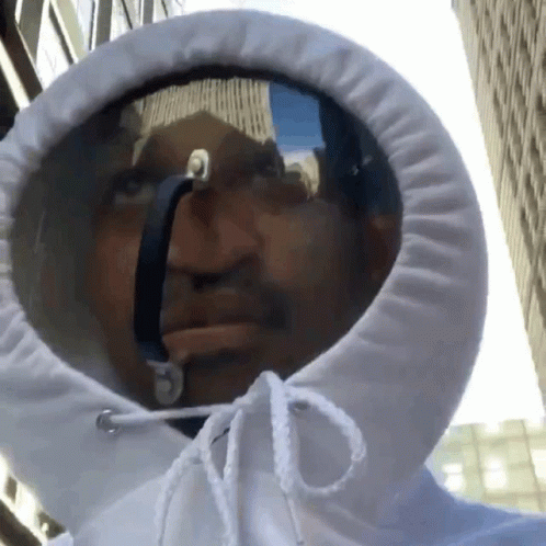 A Man Wearing A White Hoodie With A Reflection Of A Building In It GIF