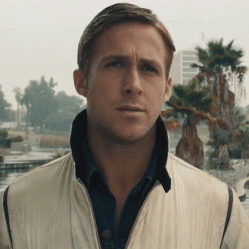 A Man Wearing A White Jacket And A Blue Shirt Looks At The Camera GIF