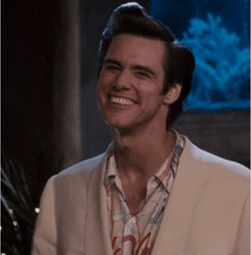 A Man Wearing A White Jacket And A Shirt With The Letter A On It Smiles GIF