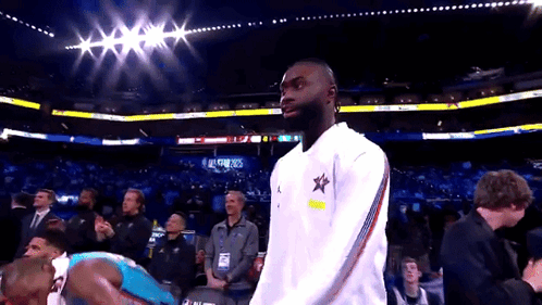 a man wearing a white jacket with a star on it stands in a stadium