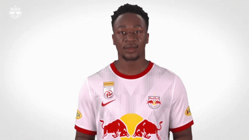 A Man Wearing A White Jersey With Red Bulls On The Front GIF