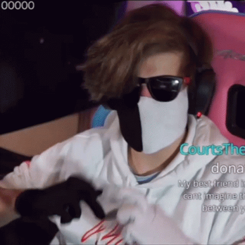 A Man Wearing A White Mask And Sunglasses Is Sitting In A Pink Chair . GIF